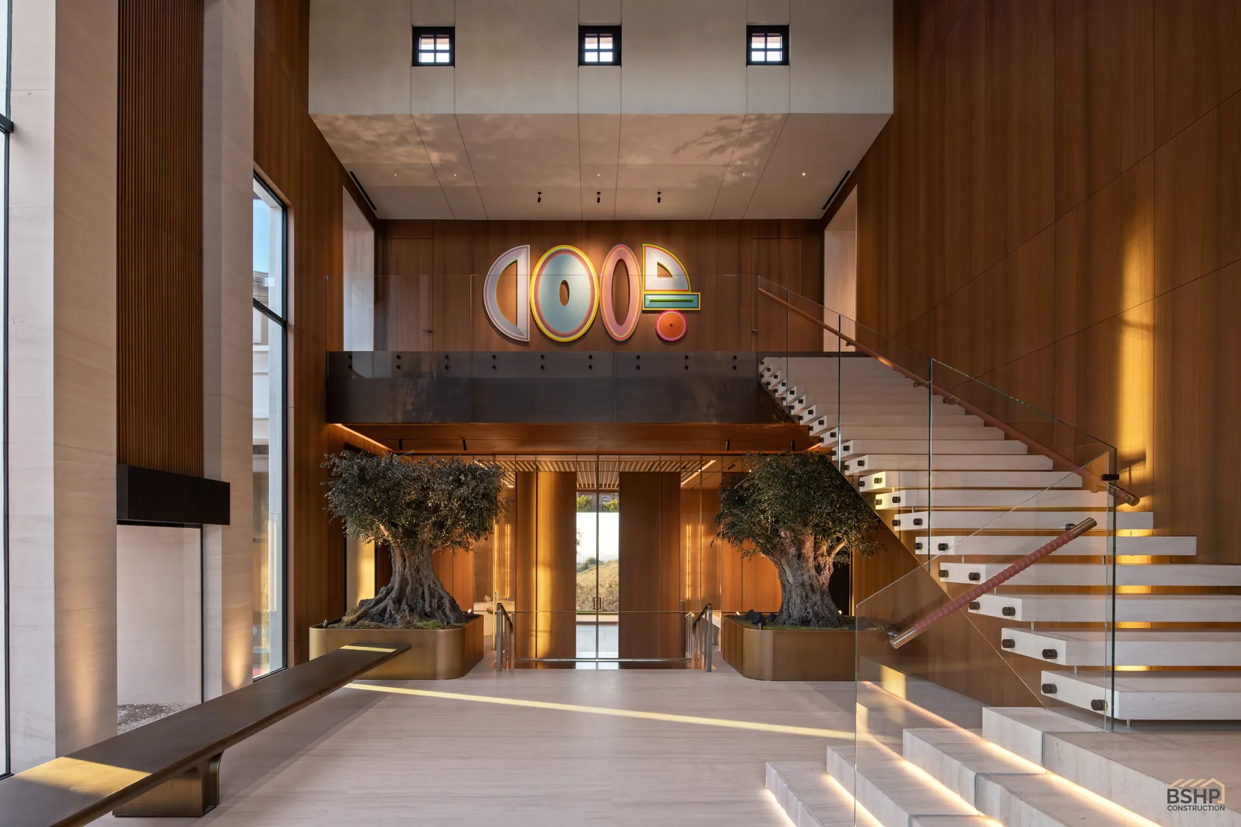 Double-height entry foyer with floating staircase, gallery bridge and olive trees