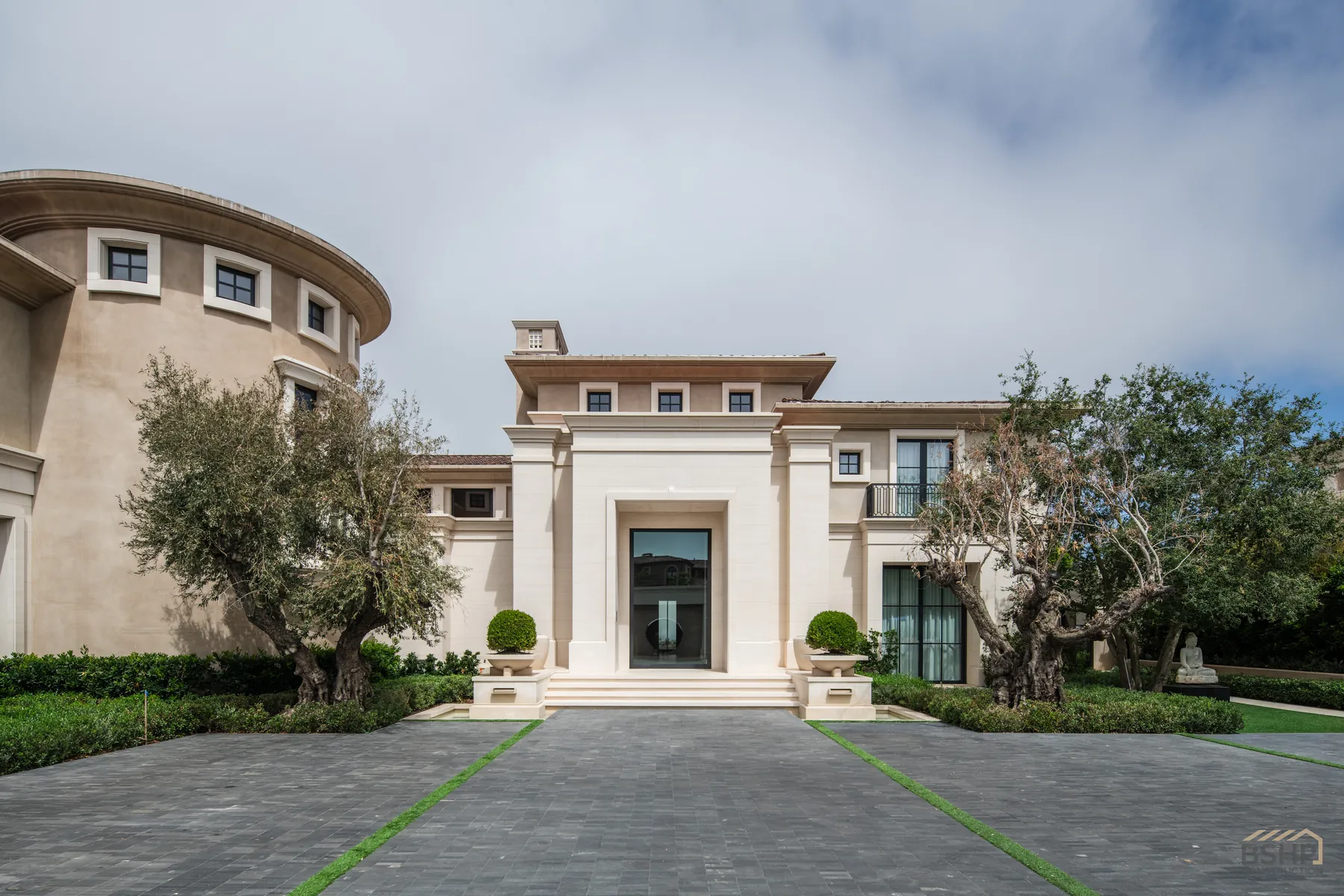 Limestone facade and olive-lined motor court at a custom Newport Coast estate built by BSHP Construction