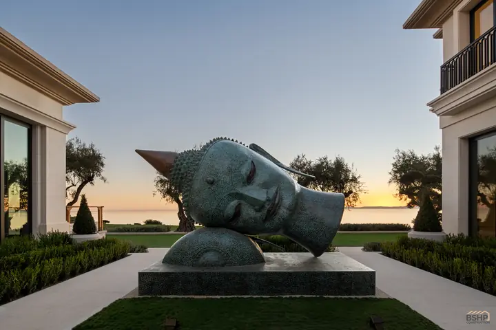 Reclining bronze head sculpture against the sunset sky