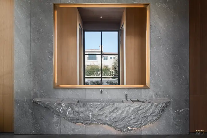 Hand-carved live-edge stone bath beneath a framed picture window