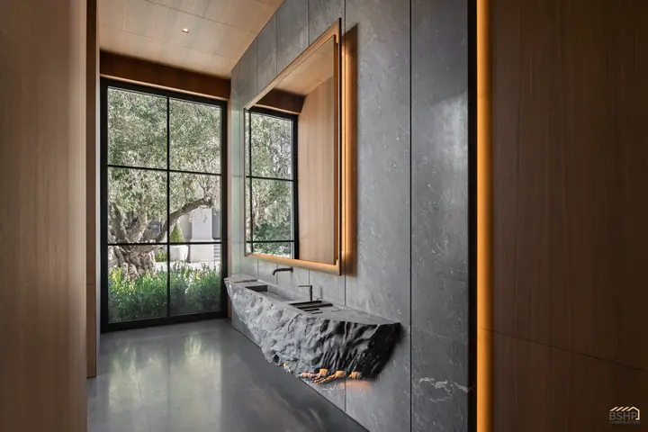 Rough-hewn carved stone basin set against a steel-framed garden window