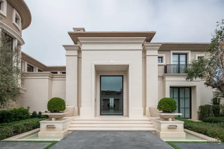 Double-height limestone entry portico with slim steel-framed glazing