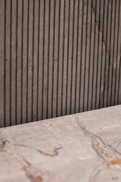 Fluted timber panelling above rose-veined marble