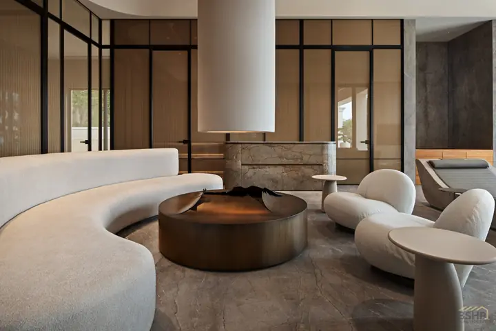 Sculpted seating gathered around a bronze fire table in the spa lounge