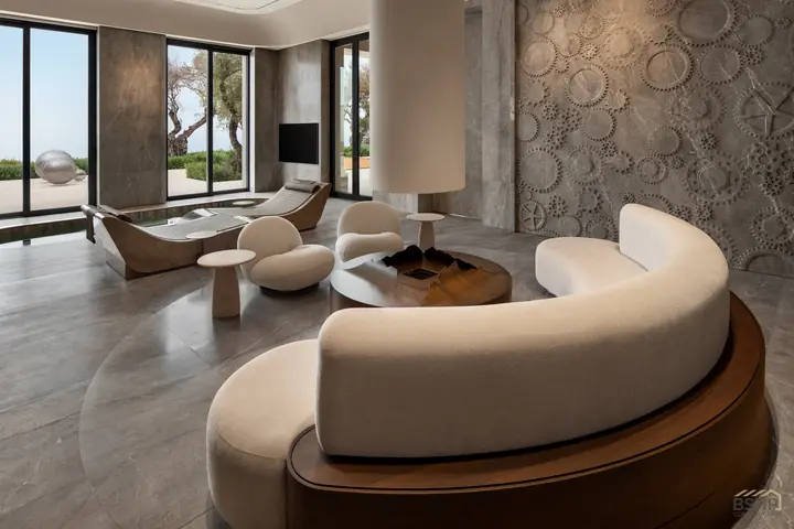 Curved bouclé sofa in the spa lounge against a hand-carved stone relief wall