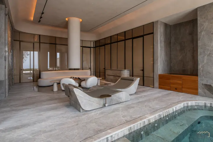 Indoor spa pool with sculpted stone loungers and book-matched marble