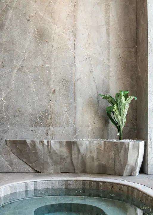 Carved stone basin with sculptural planting above the spa pool
