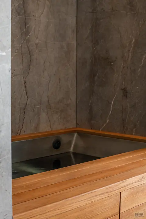 Teak-lined cold plunge set into stone