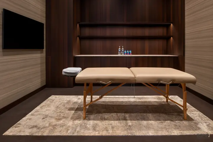 Treatment room lined in teak with a massage table and shelved wall
