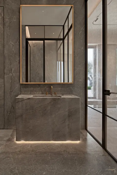 Bronze-framed mirror above a solid stone vanity plinth